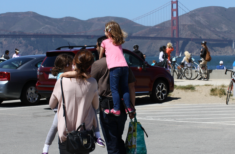 Prototype Step Caddy child carrier, worn by the inventor carrying his daughter, in front of the Golden Gate Bridge.
