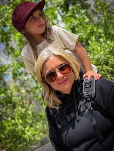 Customer Photo of a parent carrying a child with the Step Caddy child carrier - both smiling broadly. Step Caddy toddler carrier for outdoor adventures with kids, perfect for hiking and family outings.