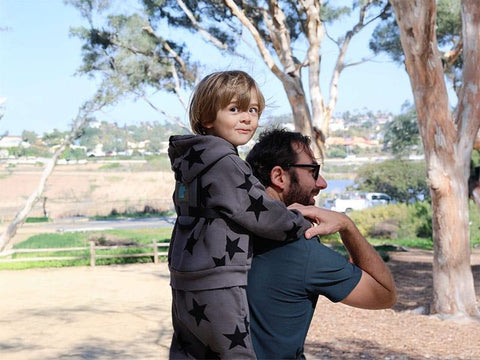 Dad carrying 4 year old son with a Step Caddy child carrier.