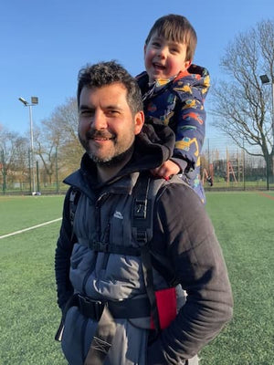 Customer Photo of a parent carrying a child with the Step Caddy child carrier - both smiling broadly.  Step Caddy toddler carrier for outdoor adventures with kids, perfect for hiking and family outings.