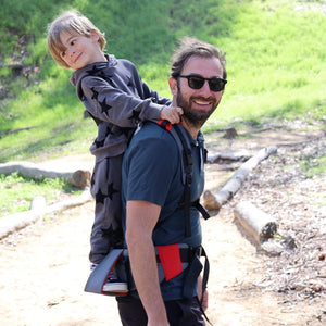 Picture of a parent carrying their child with Step Caddy child carrier - both smiling broadly.   Step Caddy child carrier, perfect preschool carrier, best hiking carrier for preschoolers.